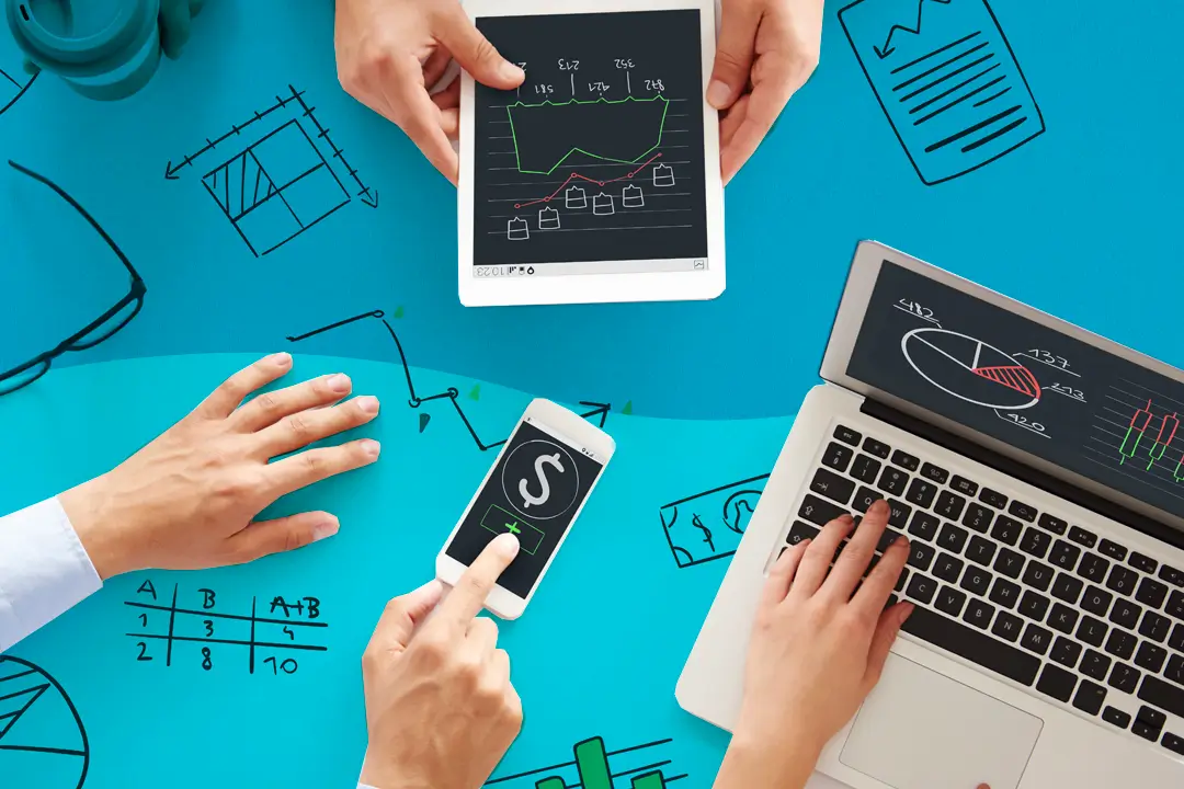 Profissionais de negócios utilizando laptops e tablets, analisando diagramas empresariais em um ambiente de trabalho colaborativo.